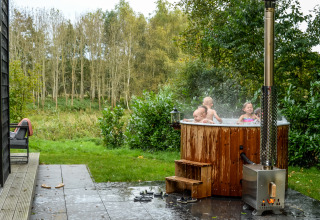 Children enjoy a hot tub beside the River Cabin tiny house at Holiday Park Mölke, Netherlands.