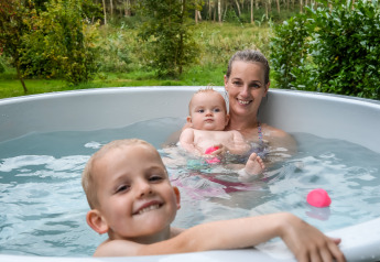 Moeder en twee kinderen genieten van het bubbelbad bij de River Cabin in Holiday Park Mölke, Nederland.