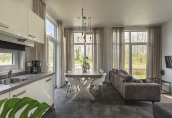Moderne tiny house bij River Cabin, Holiday Park Mölke, met keuken, eettafel en grote ramen met uitzicht.