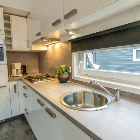 Modern tiny house kitchen at River Cabin, Holiday Park Mölke, Netherlands, with sink and gas stove.