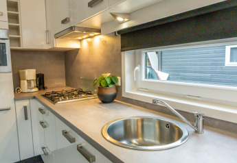 Moderne tiny house keuken in River Cabin, Holiday Park Mölke, Nederland, met spoelbak en gaskookplaat.