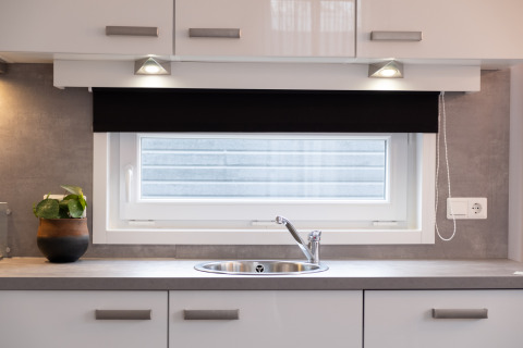Évier de cuisine moderne sous une fenêtre avec store dans une tiny house au Holiday Park Mölke, Pays-Bas.