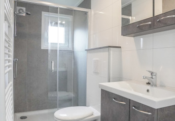Modern, compact badkamer in een tiny house bij Holiday Park Mölke met douchecabine en hangtoilet.