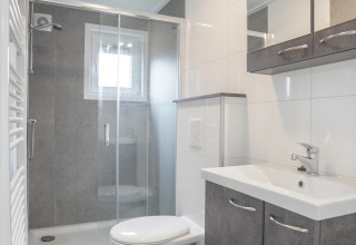 Salle de bains moderne et compacte dans une tiny house au Holiday Park Mölke avec douche et toilette murale.