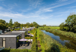 Cabaña junto al río con terraza y jacuzzi exterior en Holiday Park Mölke, rodeada de naturaleza en Holanda.
