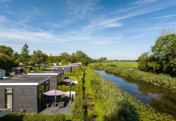 Vue sur une River Cabin, terrasse et bain à remous au bord de l’eau au Holiday Park Mölke aux Pays-Bas.