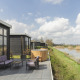 Terrasse med lilla havemøbler og udendørs vildmarksbad ved flod, ved River Cabin med udsigt over landskabet.