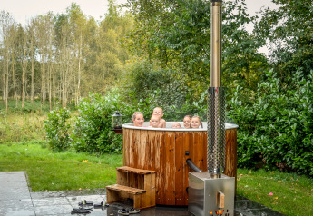 Gruppe von Menschen entspannt im Außen-Whirlpool an der River Cabin im Holiday Park Mölke, Niederlande.