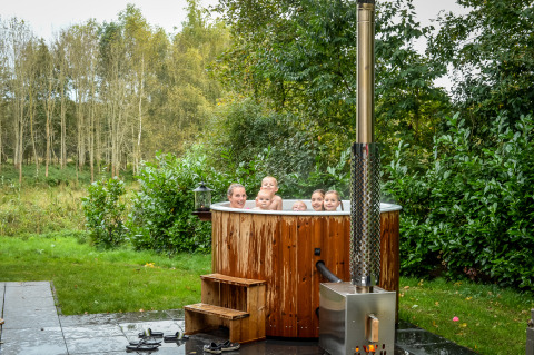 Gruppe von Menschen entspannt im Außen-Whirlpool an der River Cabin im Holiday Park Mölke, Niederlande.