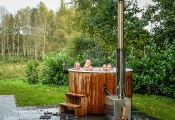 Groep mensen geniet van het warme buitenbad aan de River Cabin in Holiday Park Mölke, Nederland.