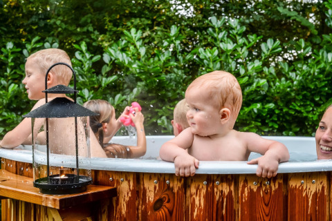 Kinder und ein Erwachsener genießen einen Whirlpool an einer kleinen Hütte im Holiday Park Mölke, Niederlande.
