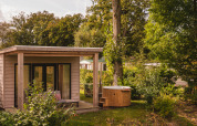 River Lodge mit Whirlpool im Holiday Park Mölke, Niederlande, umgeben von Bäumen und grüner Natur.