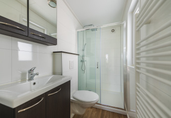 Moderne badkamer in een glamping verblijf met douche, wastafel, toilet en een houten vloer.