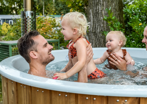 Una famiglia si rilassa insieme nella vasca idromassaggio al River Lodge del Holiday Park Mölke nei Paesi Bassi.