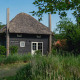 Lille hus kaldet Reggehooiberg med stråtag, sauna og varmtvandsbassin omgivet af grøn natur.