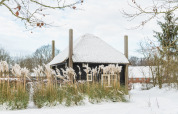 Snow-covered Reggehooiberg tiny house with sauna and hot tub at Holiday Park Mölke, Netherlands, in winter.