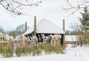 Sneeuwbedekt tiny house Reggehooiberg met sauna en hottub bij Holiday Park Mölke, Nederland, in de winter.