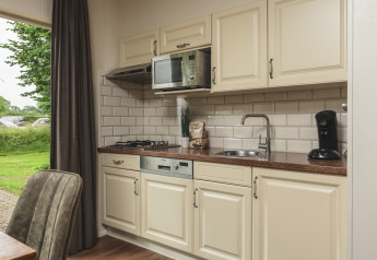 Kompakte Küche im Tiny House im Holiday Park Mölke, Niederlande, mit Geräten und Spüle.