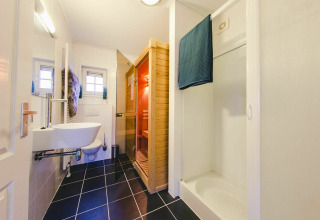 Baño moderno con ducha, sauna y tocador en una tiny house en Holiday Park Mölke, Países Bajos.