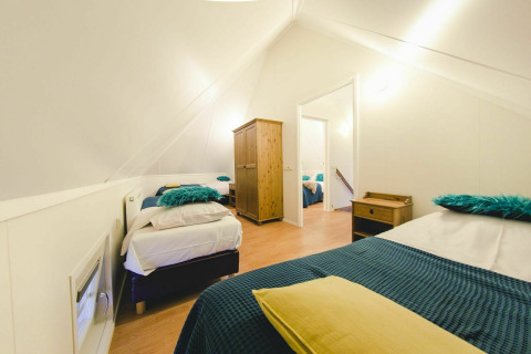 Acogedor dormitorio en una tiny house en Holiday Park Mölke, Países Bajos, con ropa de cama azul y muebles de madera.