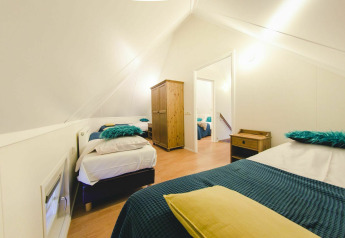 Knusse slaapkamer in een tiny house bij Holiday Park Mölke, met blauwe accenten en houten meubilair.