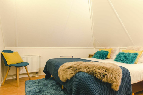 Dormitorio de tiny house en Holiday Park Mölke, Países Bajos, con cama acogedora y decoración moderna.