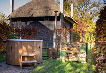 Buitenaanzicht van houten hottub, houtopslag en huisje bij Holiday Park Mölke in Nederland.