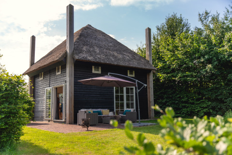Gemütliche Gruppenunterkunft Reggehooiberg mit Strohdach, Terrasse und großem Garten in grüner Umgebung.