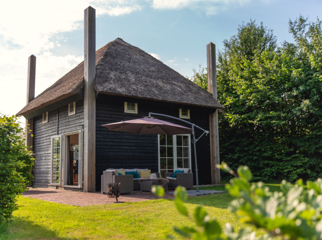 Sfeervolle groepsaccommodatie Reggehooiberg met rieten dak, terras en grote achtertuin in groene omgeving.