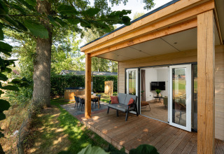 Casa pequeña de madera con terraza cubierta, asientos exteriores y jacuzzi en Holiday Park Mölke, Países Bajos.