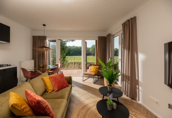 Gezellige woonkamer in een tiny house bij Holiday Park Mölke met uitzicht op de natuur en veel licht.