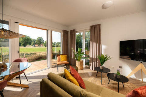 Sala luminosa en una tiny house del Holiday Park Mölke con decoración moderna y vista al campo verde.