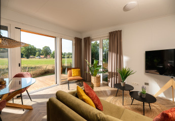 Salon lumineux d’une tiny house au Holiday Park Mölke, Pays-Bas, avec déco moderne et vue sur la campagne.