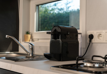 Moderne Küchenzeile mit Espressomaschine, Spüle und Gasherd in einer Nature Lodge im Holiday Park Mölke.