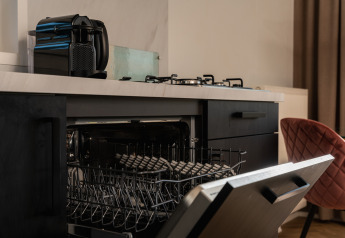 Lavastoviglie aperta in una piccola cucina con macchina da caffè e fornello in una tiny house nei Paesi Bassi.