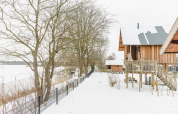 Wooden cabins in snowy landscape at Holiday Park Mölke, Regge Cottage, Netherlands, winter scene.