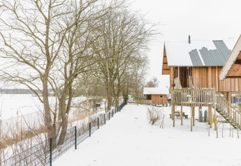 Houten huisjes in een besneeuwd landschap bij Holiday Park Mölke, Regge Cottage, Nederland, winter.