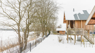 Houten cottage in een sneeuwlandschap bij Holiday Park Mölke, Regge Cottage, Nederland, wintertijd.