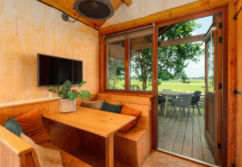 Gezellige tiny house met eethoek, tv en uitzicht op terras en veld bij Holiday Park Mölke, Nederland.