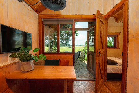 Innenaufnahme des Regge Cottage mit Holzmöbeln und Blick auf die grüne Landschaft in den Niederlanden.