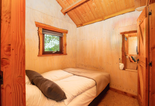 Acogedor dormitorio en Regge Cottage con paredes de madera y ventana, Holiday Park Mölke, Países Bajos.