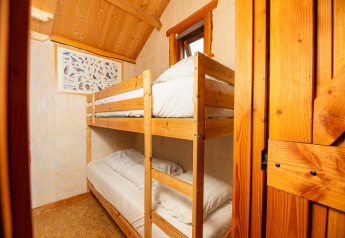 Holzhütte mit Etagenbett, weißer Bettwäsche, Fenster und Vogelposter im Regge Cottage in den Niederlanden.