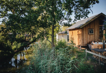 Lille træhytte ved flod, Regge Cottage med spabad i Holiday Park Mölke, Nederlandene, omgivet af natur.
