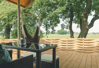 Udsigt fra terrassen på Regge Cottage med hængekøje og bord, omringet af træer hos Holiday Park Mölke.