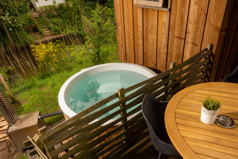 Udendørs område ved træhus med rund varmtvandskar, hegn og terrassebord i Holiday Park Mölke, Holland.
