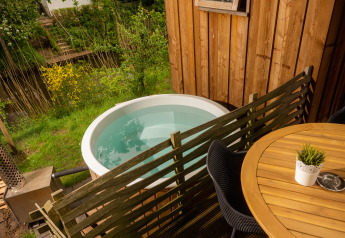 Buitenaanzicht van Regge Cottage met hottub, houten hek en tafel bij vakantiepark Mölke in Nederland.
