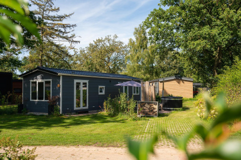 Foto de Bungalette basic con jacuzzi en Holiday Park Mölke, Países Bajos, rodeado de césped y naturaleza.