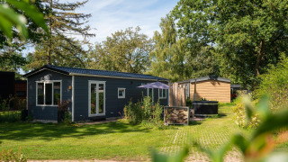 Photo du Bungalette basic avec jacuzzi au Holiday Park Mölke, Pays-Bas, entouré de verdure et d'arbres.