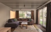 Stue med stor sofa og vinduer i Bungalette Basic med spabad på Holiday Park Mölke i Nederlandene.