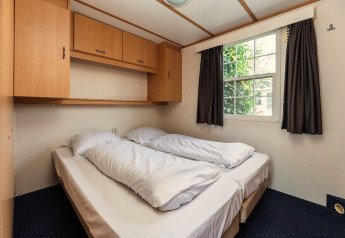 Et hyggeligt soveværelse med dobbeltseng, skabsplads og vindue i Bungalette basic + spa på Holiday Park Mölke.
